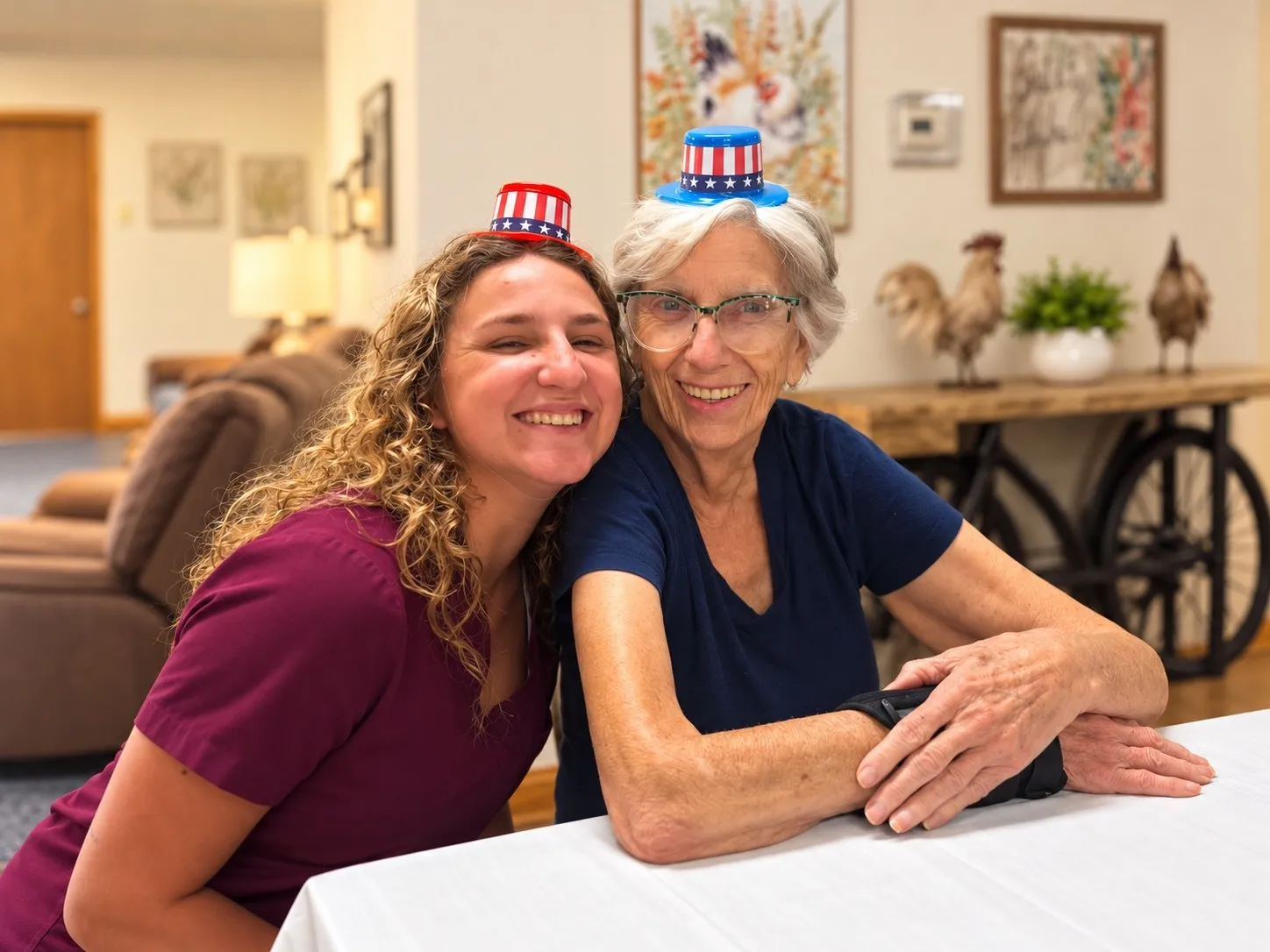A caregiver and a resident in a festive hat smiling cheek to cheek