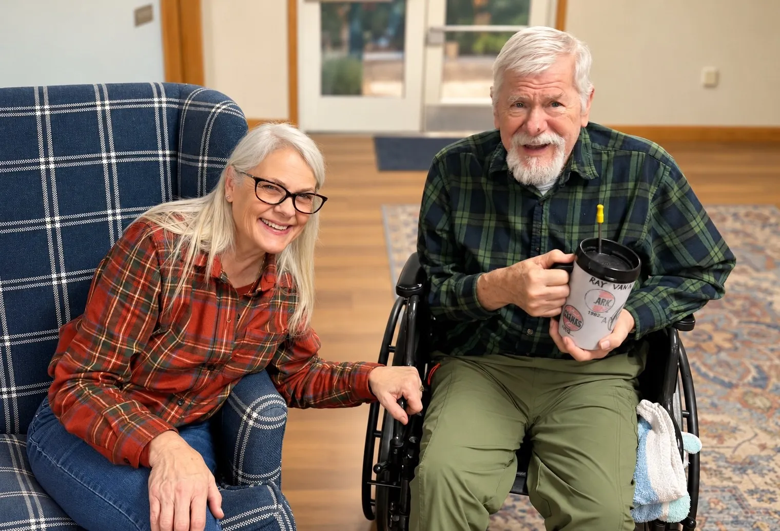 A visitor and a smiling resident with a white beard sitting together in armchairs