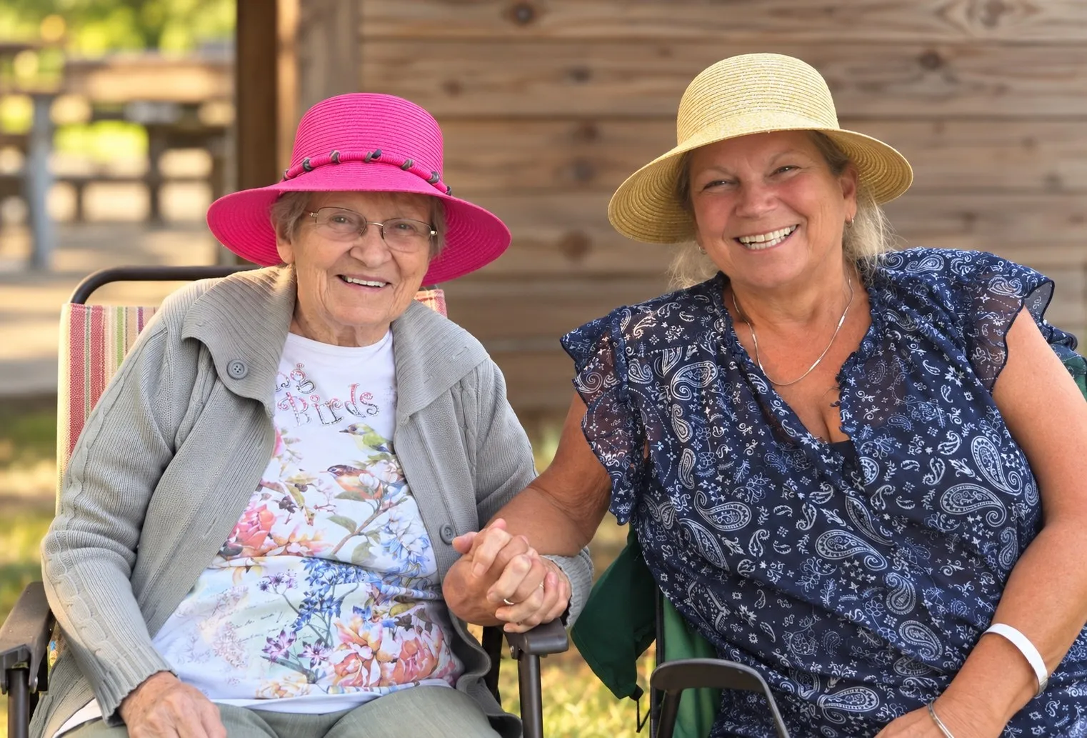 Two friends in summer hats holding hands and smiling